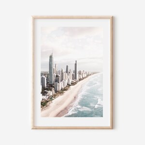 May include: An aerial view of a city skyline with tall buildings along a sandy beach with blue ocean waves.