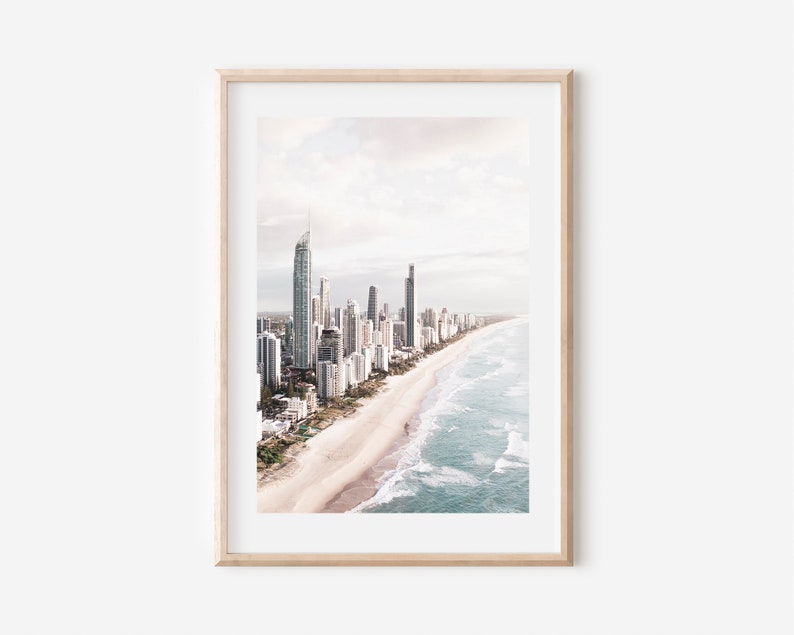 May include: An aerial view of a city skyline with tall buildings along a sandy beach with blue ocean waves.