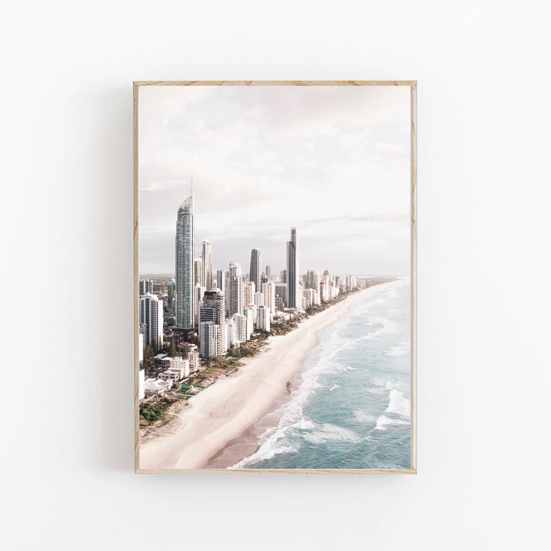 May include: An aerial view of a city skyline with tall buildings along a sandy beach with blue ocean waves.