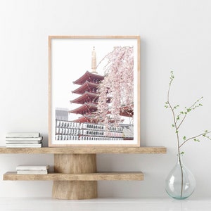 May include: A framed photograph of a red pagoda with a cherry blossom tree in the foreground. The pagoda is a traditional Japanese temple with multiple tiers. The cherry blossom tree is in full bloom, with delicate pink flowers.