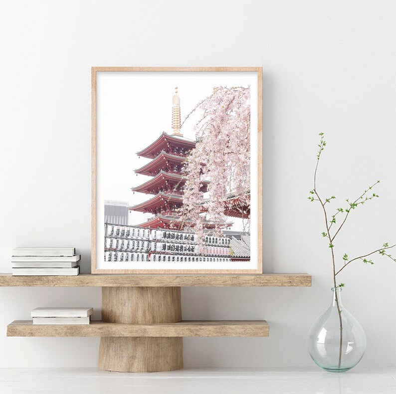 May include: A framed photograph of a red pagoda with a cherry blossom tree in the foreground. The pagoda is a traditional Japanese temple with multiple tiers. The cherry blossom tree is in full bloom, with delicate pink flowers.