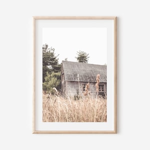 Peut inclure: Une photographie encadr&eacute;e d'une cabane en bois rustique avec un toit us&eacute;, entour&eacute;e de hautes herbes et d'arbres. L'image est dans un style vintage avec des couleurs douces.