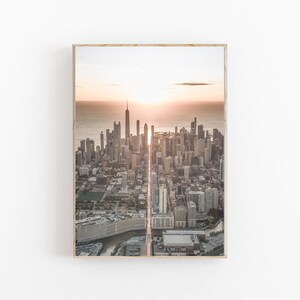 May include: An aerial view of a city skyline at sunrise. The sun is shining brightly behind the tall buildings, creating a golden glow over the city. The buildings are all different heights and shapes, and there are many trees and parks in the city.
