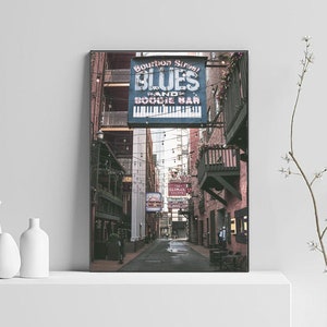Puede incluir: Un letrero vintage para "Bourbon Street Blues Piano and Boogie Bar" cuelga sobre un callej&oacute;n estrecho y adoquinado. El letrero es azul con letras blancas y presenta un gr&aacute;fico de teclado de piano. El callej&oacute;n est&aacute; iluminado con luces de cadena y tiene un ambiente r&uacute;stico y urbano.