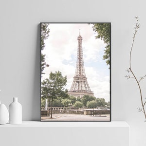 May include: A black and white photo of the Eiffel Tower in Paris, France. The tower is seen from a distance, with trees and a street in the foreground.
