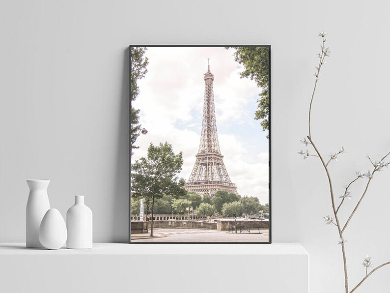 May include: A black and white photo of the Eiffel Tower in Paris, France. The tower is seen from a distance, with trees and a street in the foreground.