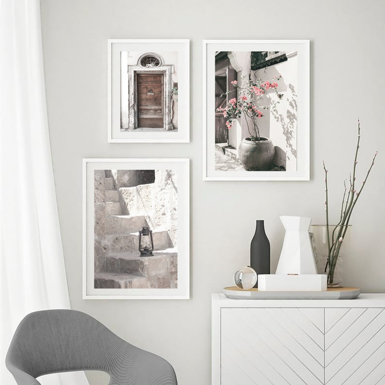 May include: Three framed prints with a white background. The first print shows a wooden door with a white frame. The second print shows a potted plant with pink flowers. The third print shows a set of stone steps with a lantern.