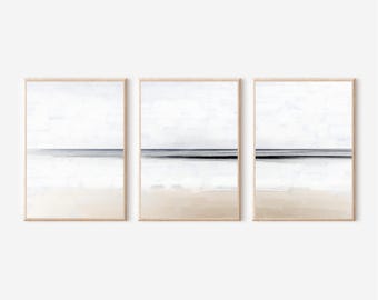 May include: Set of three abstract landscape paintings with a minimalist design. Each painting features a horizontal line representing the horizon, with a light blue sky above and a beige beach below. The horizon line is a darker blue, suggesting water.
