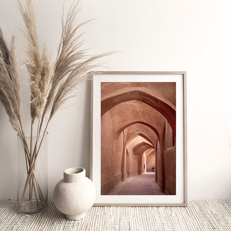 May include: A framed photograph of a narrow, arched hallway with terracotta walls. The hallway is lit by natural light, creating a warm and inviting atmosphere.