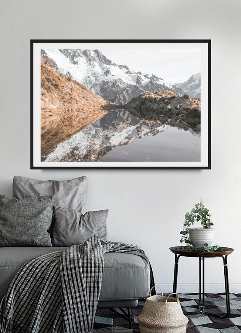 Puede incluir: Una fotograf&iacute;a enmarcada de un lago de monta&ntilde;a con monta&ntilde;as cubiertas de nieve que se reflejan en el agua. Las monta&ntilde;as son de color marr&oacute;n claro y el agua es de color azul claro.