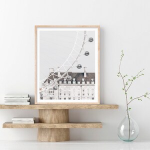 May include: A black and white photograph of the London Eye Ferris wheel with a building in the foreground. The Ferris wheel is partially visible in the image.