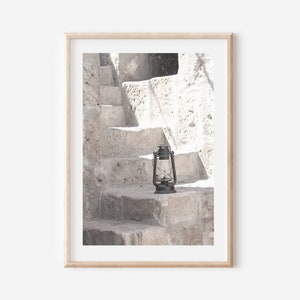 May include: A black lantern sits on a stone step in front of a white stone staircase.