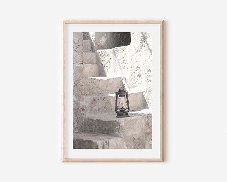 May include: A black lantern sits on a stone step in front of a white stone staircase.