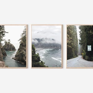 May include: Set of three framed landscape prints. The prints feature coastal and forest scenes with muted tones. One print shows a rocky coastline, another a misty beach, and the third a road through a forest with a sign that reads "Welcome to Oregon."