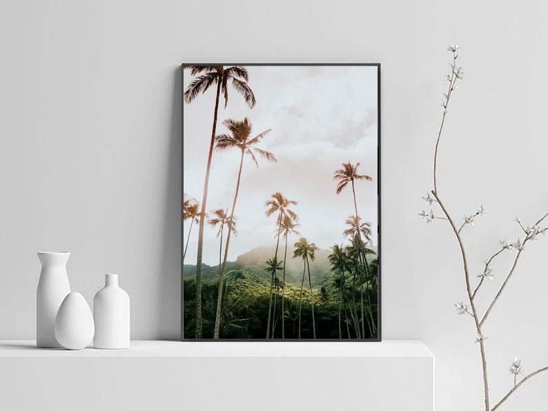 May include: A framed photograph of a tropical landscape with tall palm trees against a cloudy sky. The trees are silhouetted against a bright, orange sunset.