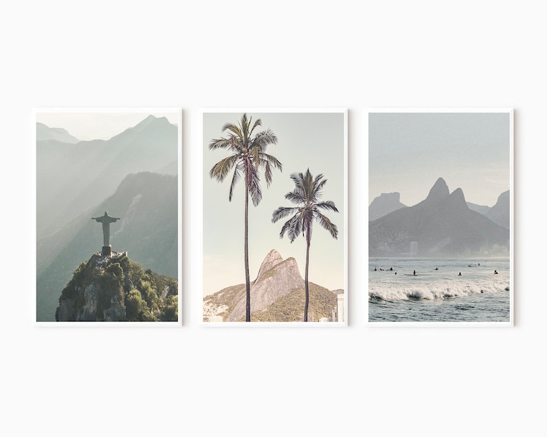 May include: A set of three minimalist landscape prints featuring a mountain range, palm trees, and a beach scene with surfers. The prints are in muted tones of blue and gray.