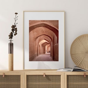 May include: A photograph of a narrow, arched hallway with a light brown, sandy color. The hallway is lined with arches on both sides, creating a sense of depth and perspective.