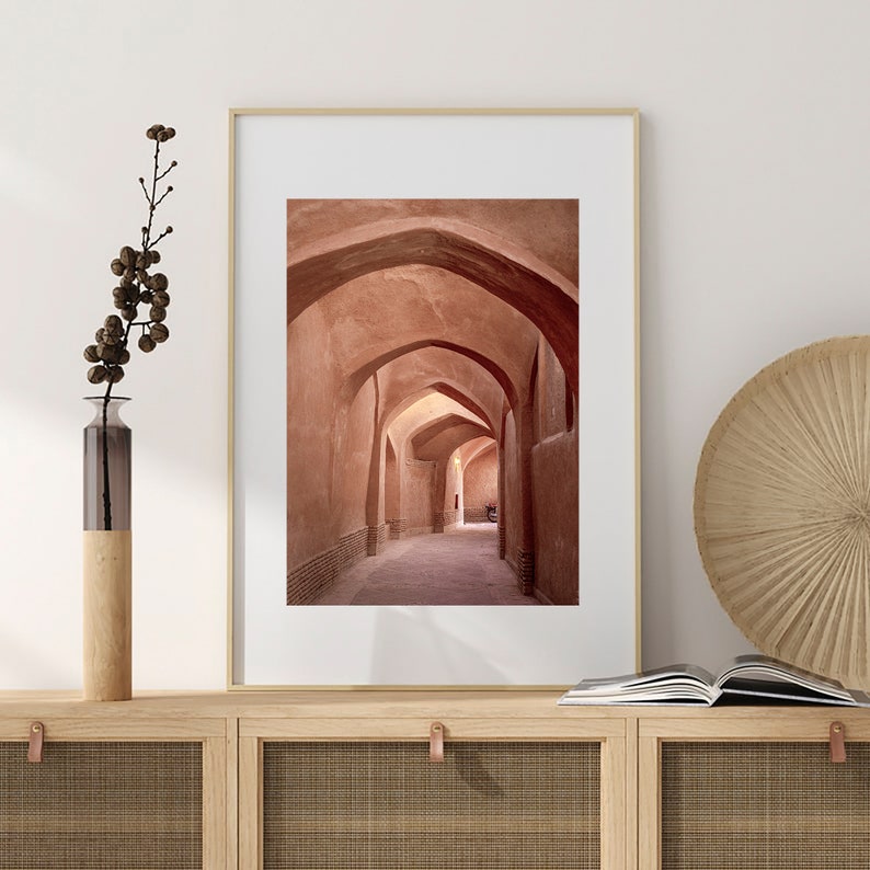 May include: A photograph of a narrow, arched hallway with a light brown, sandy color. The hallway is lined with arches on both sides, creating a sense of depth and perspective.