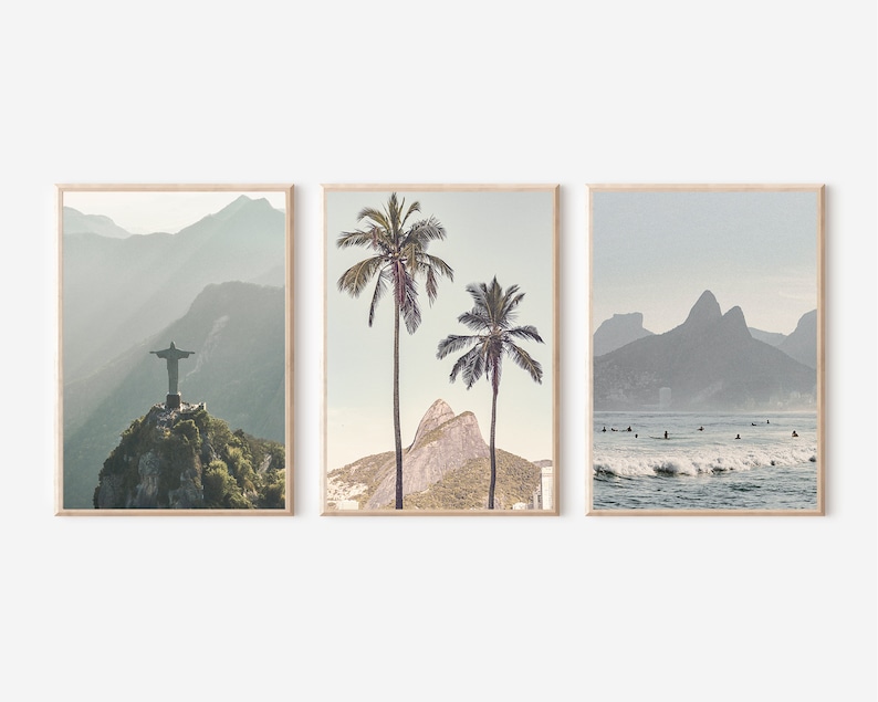 May include: A set of three framed prints featuring scenic views of Rio de Janeiro, Brazil. The first print shows the Christ the Redeemer statue on top of a mountain with a misty background. The second print shows two palm trees in front of a mountain with a blue sky. The third print shows a beach scene with surfers in the water and mountains in the background.