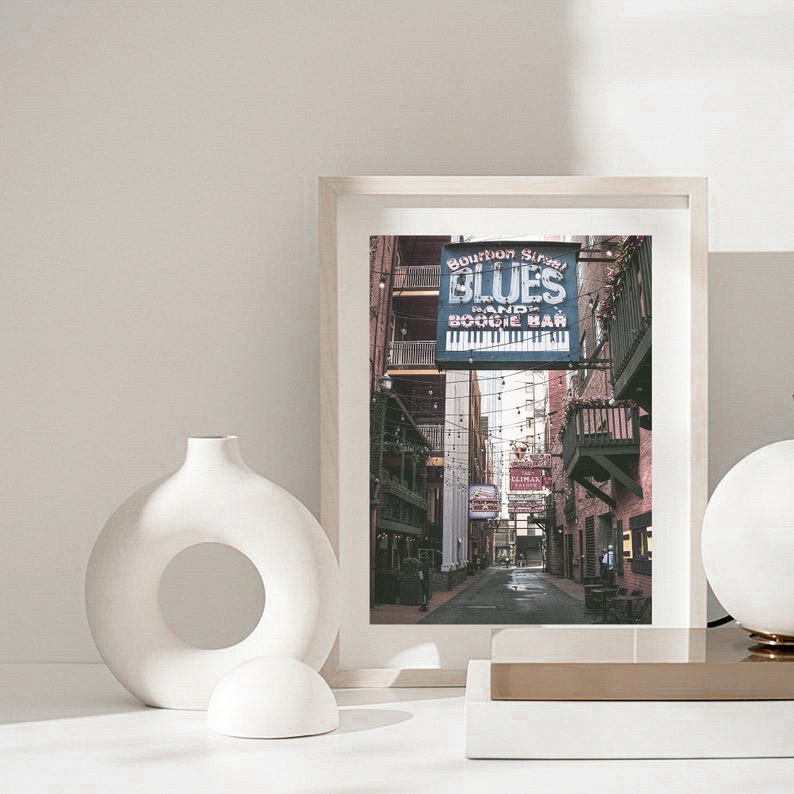 Puede incluir: Una fotograf&iacute;a enmarcada de un callej&oacute;n estrecho en Nueva Orleans, Luisiana. El callej&oacute;n est&aacute; bordeado de edificios de ladrillo y tiene un letrero que dice "Bourbon Street Blues Band and Boogie Bar".