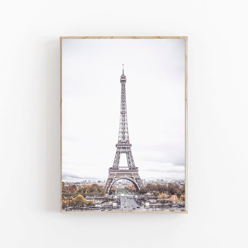 May include: A black and white photograph of the Eiffel Tower in Paris, France. The tower is in the center of the image and is surrounded by trees and buildings. The sky is cloudy and the image has a vintage feel.