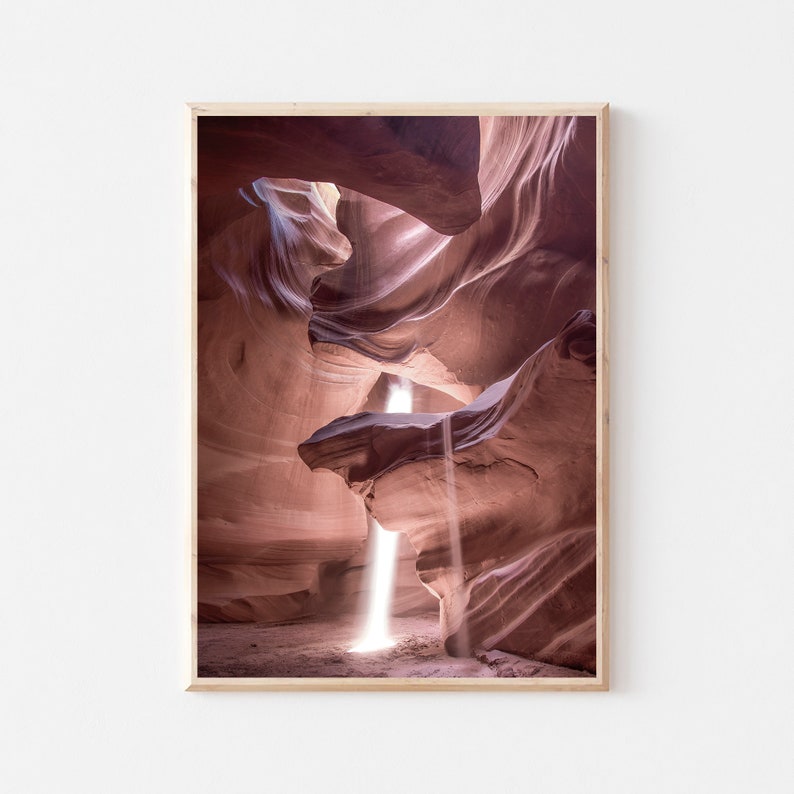 May include: A narrow canyon with smooth, red rock walls. A beam of sunlight shines through a small opening at the top of the canyon, illuminating the dusty floor.