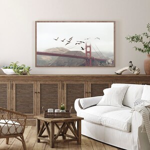 Puede incluir: Una fotograf&iacute;a enmarcada del Puente Golden Gate en San Francisco, California. El puente es rojo y tiene niebla en el fondo. Hay p&aacute;jaros volando sobre el puente.
