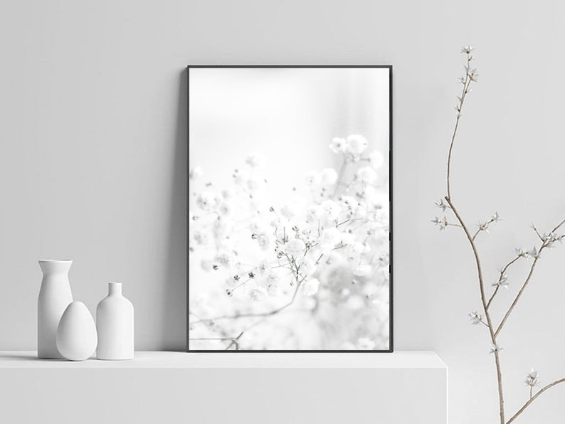 Pode incluir: Uma fotografia a preto e branco de um delicado cacho de flores brancas, com um fundo suave e desfocado. A imagem est&aacute; enquadrada numa moldura preta.