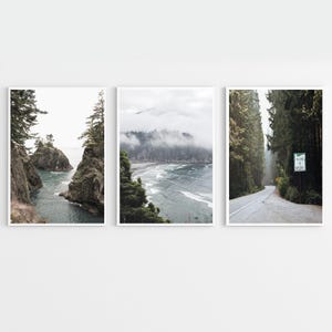 May include: Set of three framed landscape prints. The first print shows a rocky coastline with turquoise water. The second print depicts a misty coastal scene. The third print features a road winding through a forest with a sign.