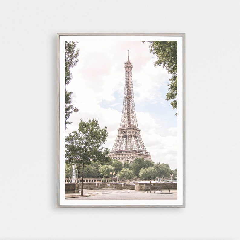 May include: A framed photograph of the Eiffel Tower in Paris, France. The tower is visible through a frame of trees. The photo is taken from a street level perspective.