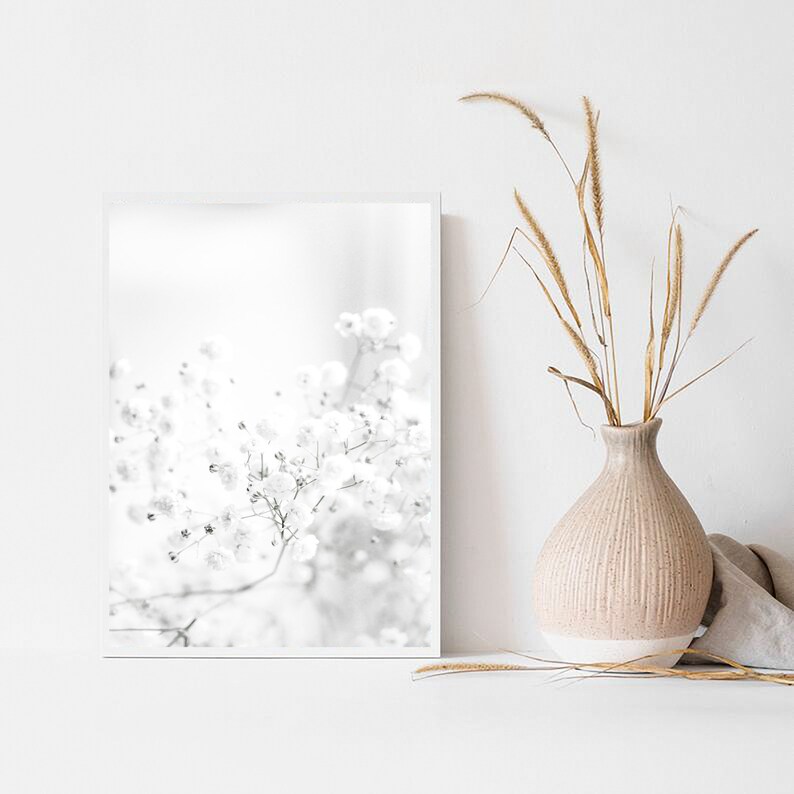 Pode incluir: Uma fotografia a preto e branco de um arranjo floral delicado num estilo minimalista. A imagem apresenta um &uacute;nico ramo de flores brancas com um fundo desfocado.