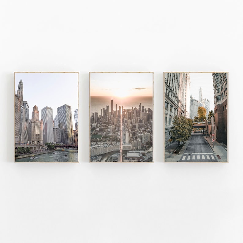 May include: Three framed photographs of Chicago cityscapes. The first image shows a view of the city skyline from the river. The second image shows a wide aerial view of the city skyline. The third image shows a street scene with buildings on either side.
