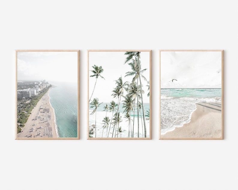 Pode incluir: Conjunto de tr&ecirc;s impress&otilde;es de praia emolduradas. A primeira mostra uma vista a&eacute;rea costeira com edif&iacute;cios e uma praia. A segunda apresenta palmeiras. A terceira mostra ondas numa praia arenosa com p&aacute;ssaros no c&eacute;u.