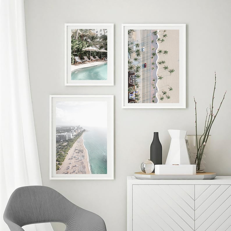 May include: Three framed photographs of aerial views of a beach with palm trees, a swimming pool, and a city skyline.