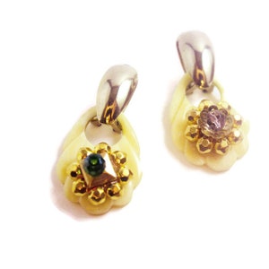May include: A pair of gold and white earrings with a flower design and green and clear gemstones.