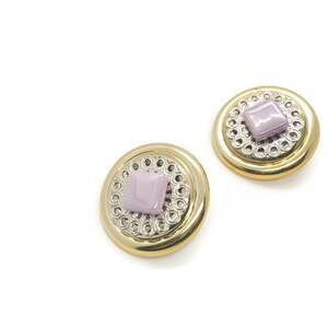 May include: A pair of gold-tone earrings with a silver-tone filigree design and a light purple square-shaped stone in the centre of each earring.