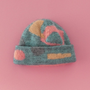 May include: A teal blue knitted beanie with a geometric pattern in pink, orange, and gray.