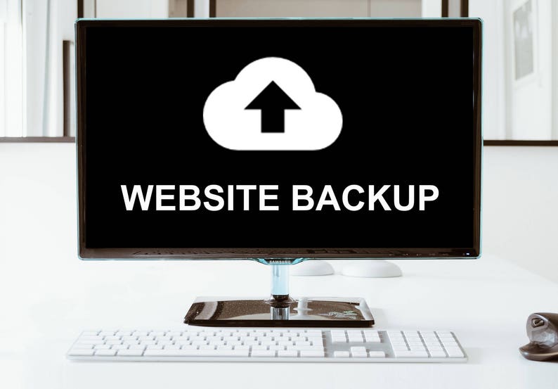 May include: A computer monitor displaying a white cloud icon with an upward arrow, and the text "WEBSITE BACKUP" on a black background. A white keyboard and a black mouse are on the desk in front of the monitor.