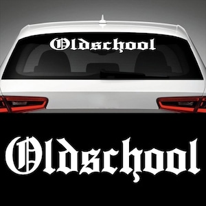 May include: White vinyl decal with the word "Oldschool" in a gothic font style. The decal is applied to the rear window of a white car.