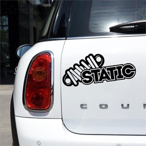 Könnte beinhalten: Schwarz-weißer Autoaufkleber mit einer Schraubenfeder und dem Wort "STATIC" in fetten Buchstaben.