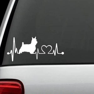 Könnte beinhalten: Weißer Vinyl-Aufkleber mit der Silhouette eines Yorkshire Terriers, einer Herzschlaglinie und einem Herzen. Der Aufkleber befindet sich auf einer schwarzen Autotür.