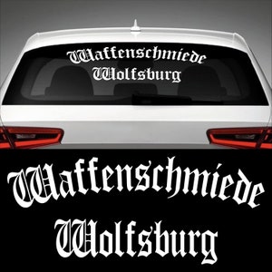 Könnte beinhalten: Weißer Vinyl-Aufkleber mit dem Text "Waffenschmiede Wolfsburg" in gotischer Schriftart. Der Aufkleber ist auf der Heckscheibe eines Autos zu sehen.