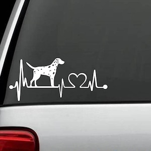 May include: White vinyl decal showing a Dalmatian dog silhouette with black spots, incorporated into a heartbeat line design. The design includes a heart symbol, creating a pet-themed graphic. Suitable for car windows or other smooth surfaces.