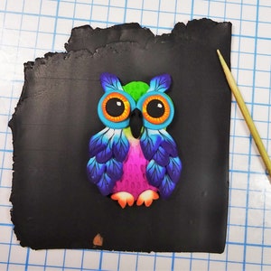May include: A colorful owl figurine with blue, green, pink, and orange accents. The owl is made of polymer clay and has a detailed design.
