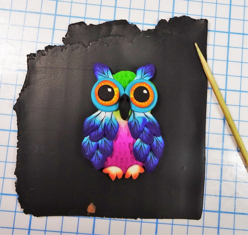May include: A colorful owl figurine with blue, green, pink, and orange accents. The owl is made of polymer clay and has a detailed design.