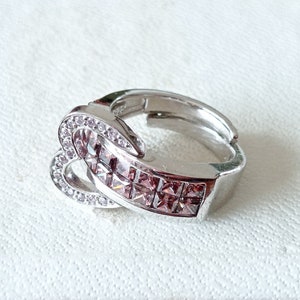 Könnte beinhalten: Ein silberner Ring mit einem herzförmigen Design und rosa und klaren Kristallen.