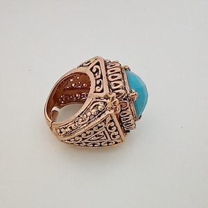 Peut inclure: Une bague en or avec un motif orné et une pierre bleu turquoise.