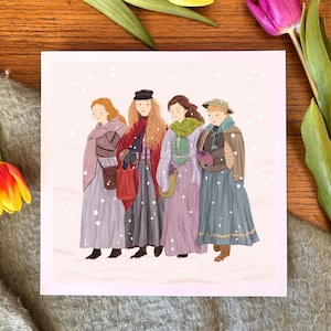 Puede incluir: Una impresión cuadrada con una ilustración de cuatro mujeres con ropa de invierno vintage, caminando en una escena nevada. Las mujeres llevan faldas largas, abrigos y sombreros. La impresión está rodeada de tulipanes y una manta gris sobre una superficie de madera.