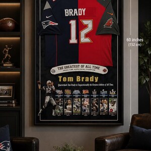 May include: Framed Tom Brady jersey, 36 x 60 inches, featuring his name and number 12. The jersey is split into navy blue and red sections. The frame includes text: "THE GREATEST OF ALL TIME" and images of Brady.