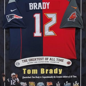 May include: Framed jersey of Tom Brady, split design with New England Patriots and Tampa Bay Buccaneers colors. Features the name "BRADY" and the number "12". Includes text: "SEVEN-TIME SUPER BOWL CHAMPION, 5-TIME SUPER BOWL MVP".